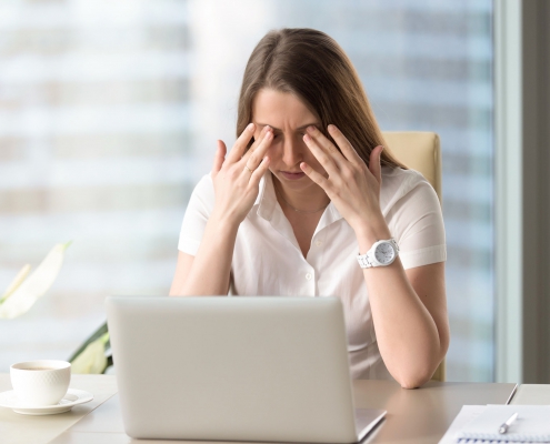 یک زن در محل کار دارای خستگی چشم و سر درد