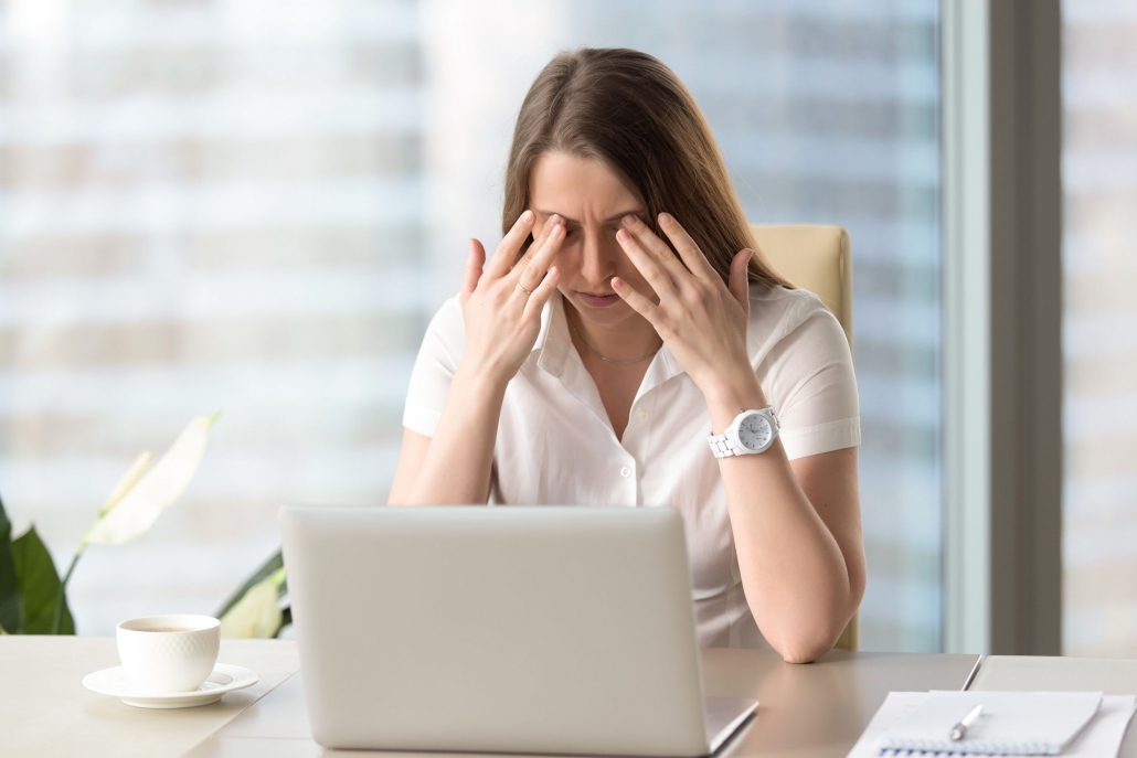 یک زن در محل کار دارای خستگی چشم و سر درد