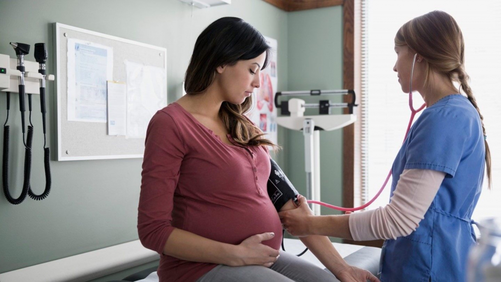 یک دکتر در حال اندازه گیری فشار خون یک زن باردار